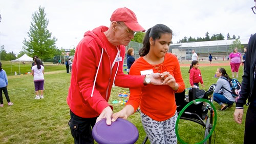 Image shows a TSVI showing a student how to throw a frisbee.