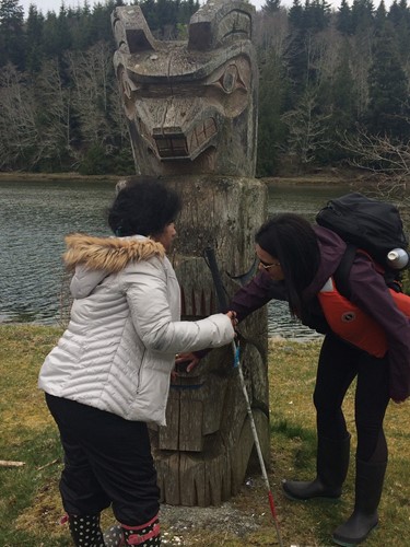 Photo shows a student and a teacher exploring a totem pole.