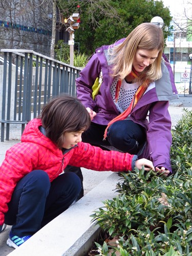 Photo shows a student and teacher exploring a shrubbery together.